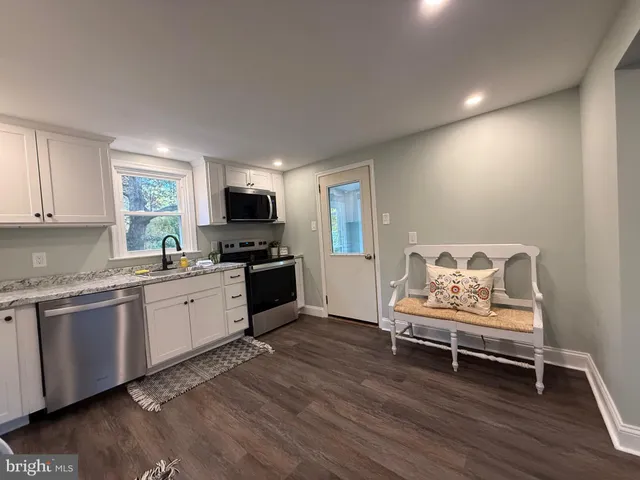 a kitchen with granite countertop a stove a sink and a microwave