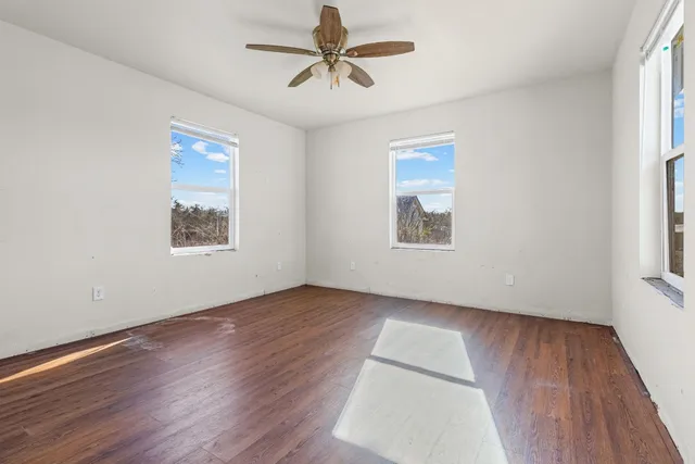 an empty room with wooden floor and windows