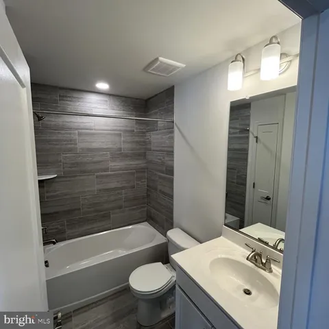 a bathroom with a bathtub shower sink vanity mirror and toilet