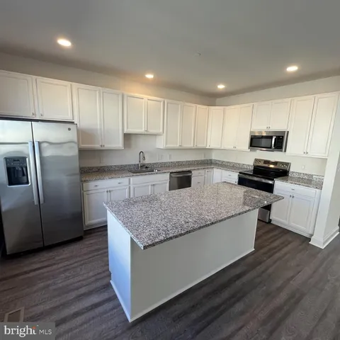 a kitchen with kitchen island granite countertop stainless steel appliances and wooden cabinets