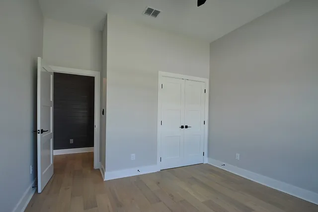 a view of an empty room with wooden floor and closet