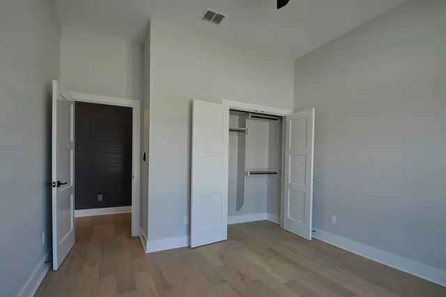 a view of an empty room with closet and wooden floor