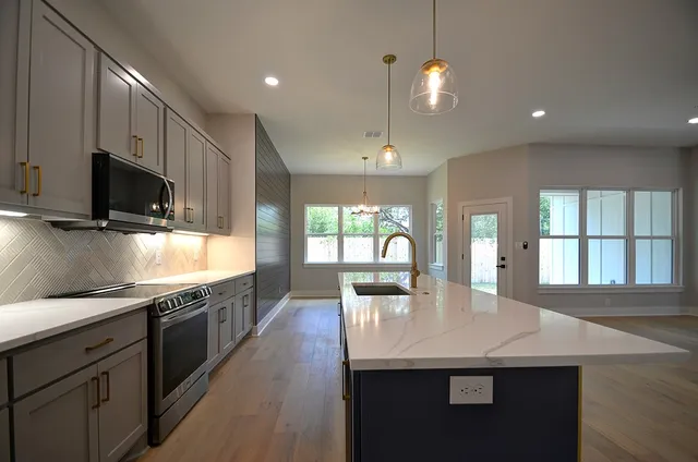a kitchen with stainless steel appliances granite countertop a sink a stove and a wooden floors
