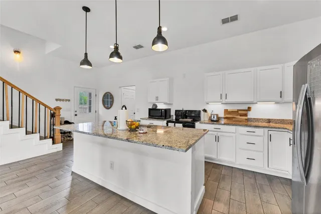 a kitchen with stainless steel appliances kitchen island granite countertop a sink a stove a dining table and chairs
