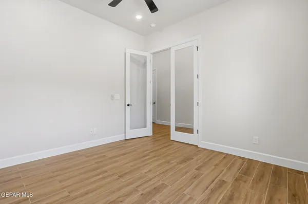 an empty room with wooden floor chandelier fan and windows