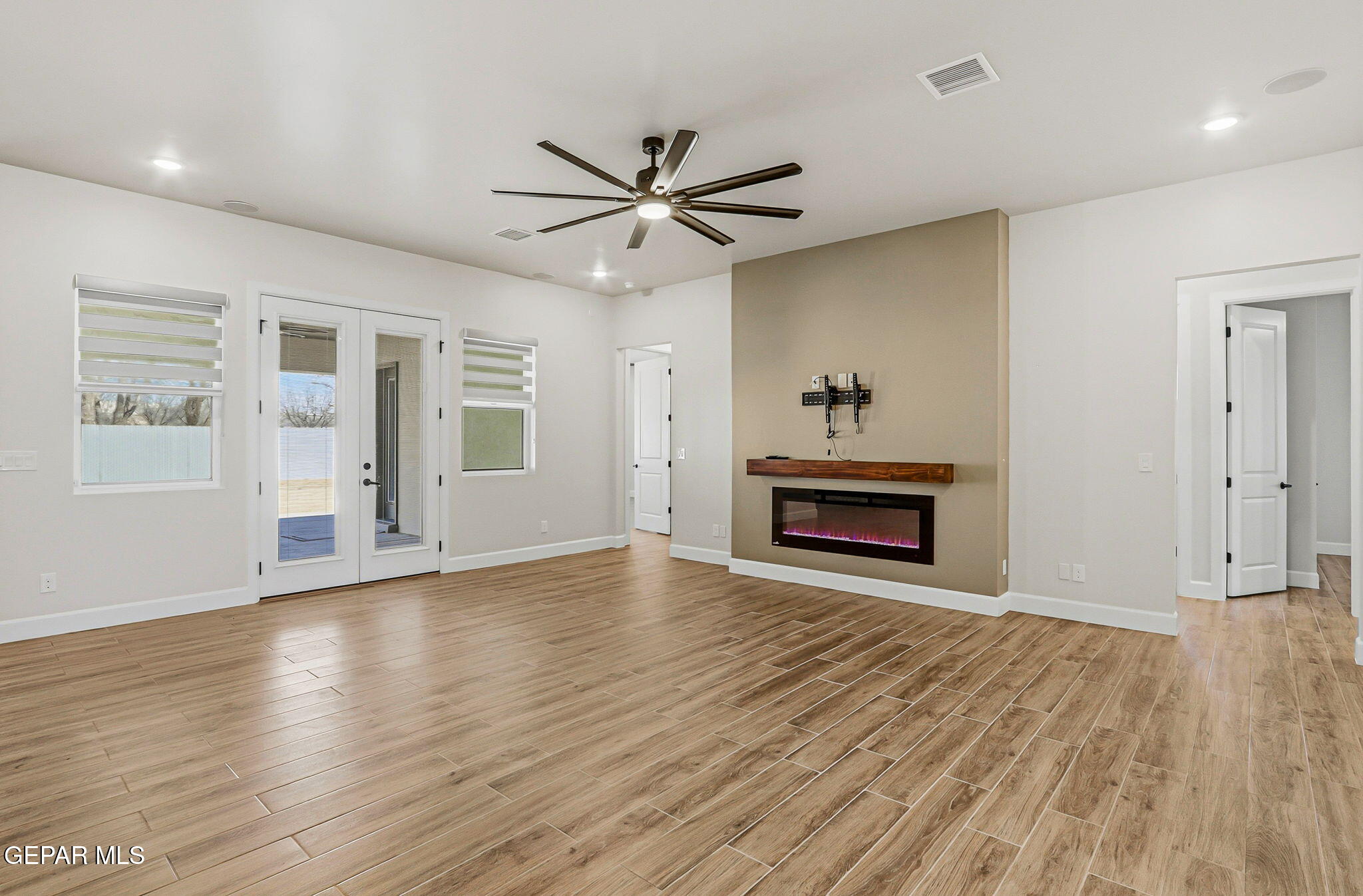 12329 Sugden Road Clint, TX 79836 - Photo 28 of 101 an empty room with wooden floor a ceiling fan a fireplace and windows