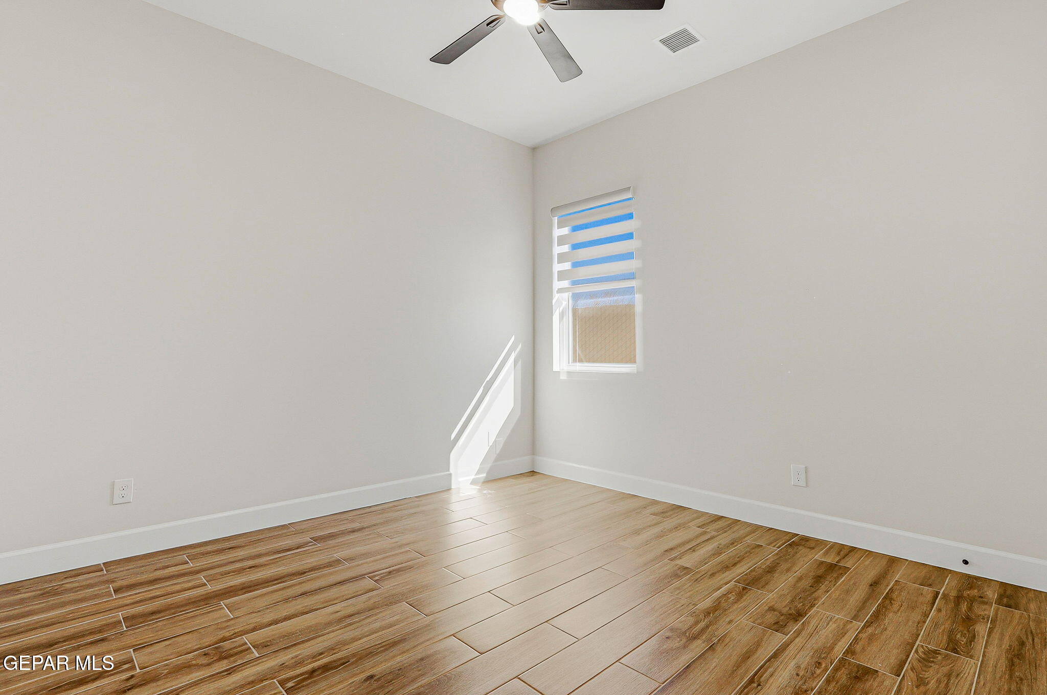 12329 Sugden Road Clint, TX 79836 - Photo 63 of 101 an empty room with wooden floor chandelier fan and windows