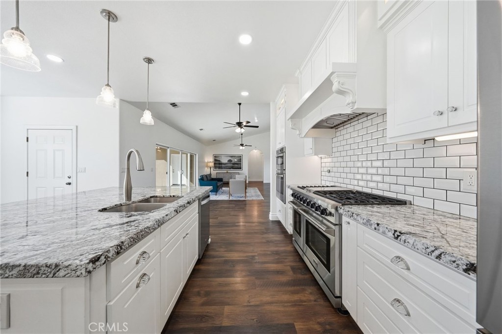 13925 Noble Way Red Bluff, CA 96080 - Photo 12 of 57 a large kitchen with granite countertop a stove top oven a sink a counter space and cabinets