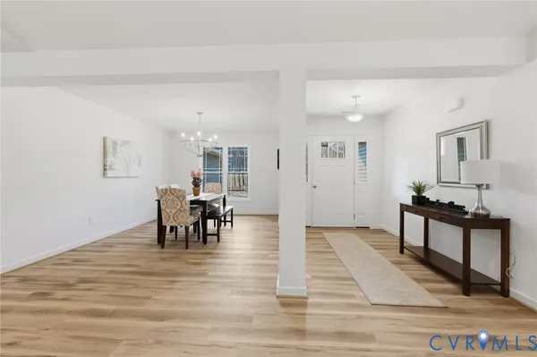 a dining room with wooden floor a chandelier a wooden table and chairs