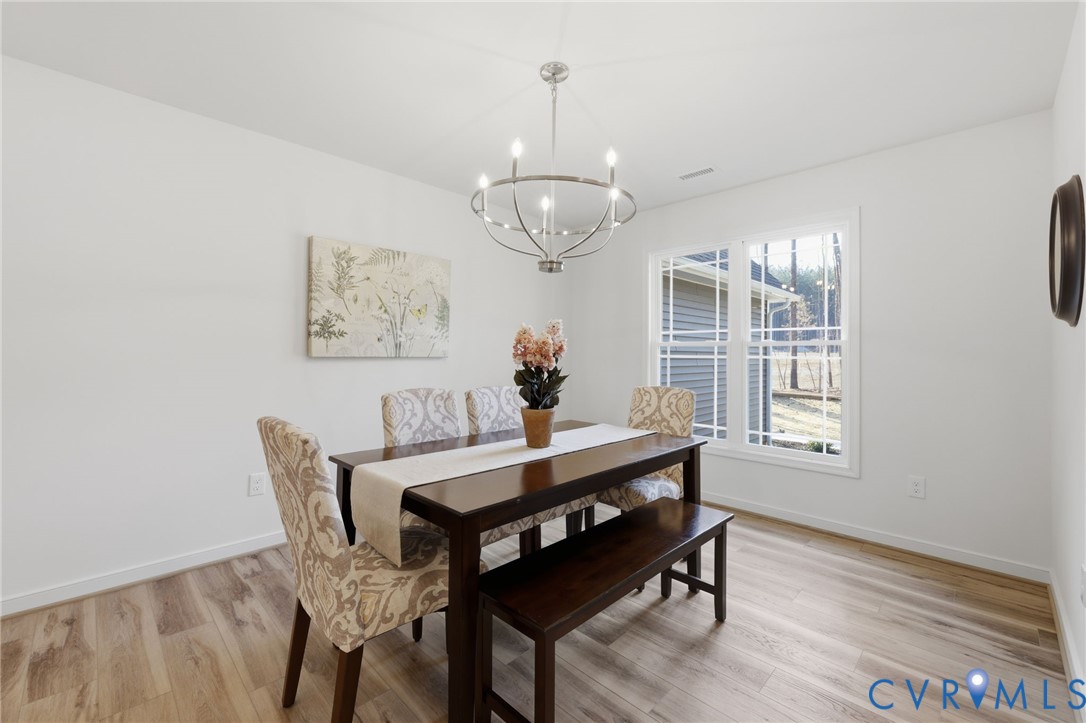 2214 Walnut Tree Boulevard Powhatan, VA 23139 - Photo 7 of 30 a dining room with wooden floor a chandelier a wooden table and chairs
