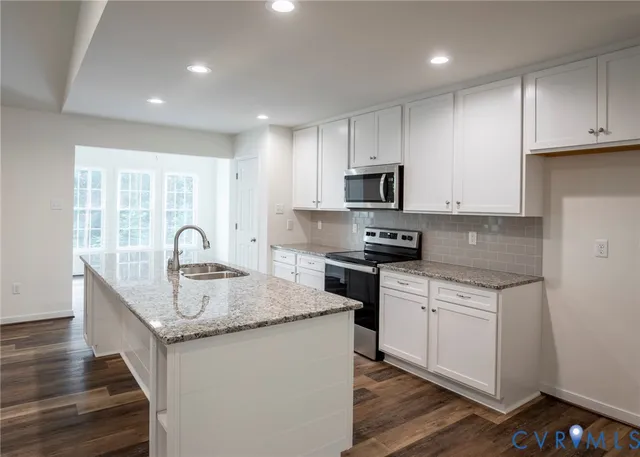 a kitchen with granite countertop a sink a stove and cabinets