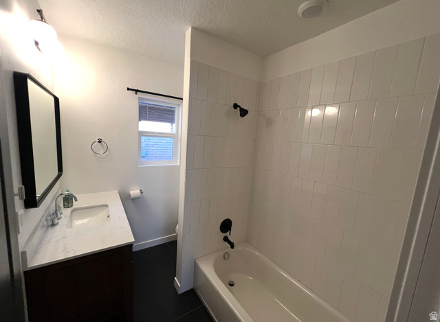 545 23rd Street Ogden, UT 84401 - Photo 14 of 28 Bathroom featuring a white subway tile shower surround with matte black fixtures, a white bathtub, a dark wood-finish vanity with a light countertop, and a rectangular framed mirror