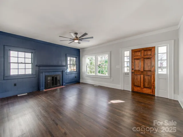 an empty room with windows fireplace and wooden floor