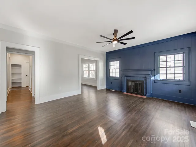 an empty room with wooden floor fireplace and windows