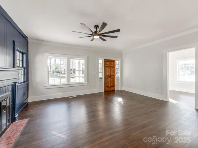 a view of an empty room with window and wooden floor