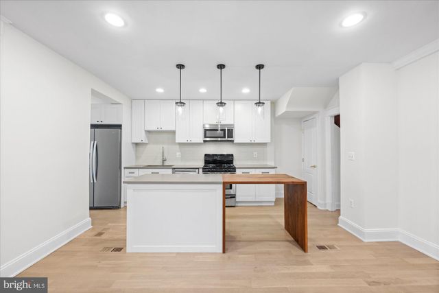 a kitchen with stainless steel appliances granite countertop a sink a stove a refrigerator and white cabinets