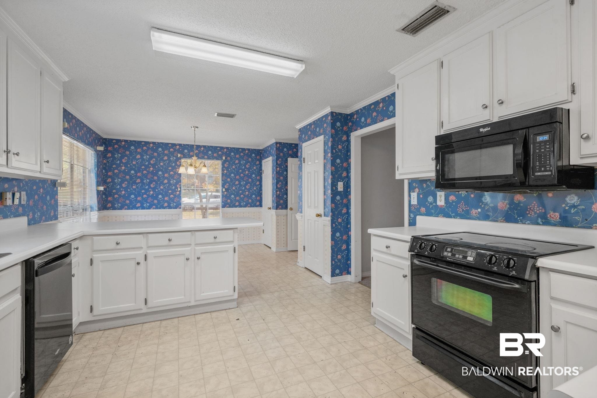 1340 Wellsley Court Mobile, AL 36695 - Photo 17 of 37 Kitchen with wallpapered walls, black appliances, white cabinetry, a chandelier, and light countertops