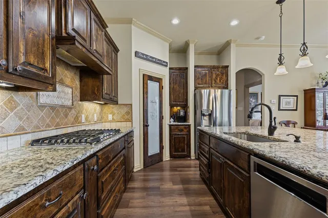 a kitchen with stainless steel appliances granite countertop a sink a stove and a wooden floors