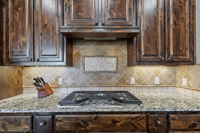 a kitchen with granite countertop a stove a sink and cabinets
