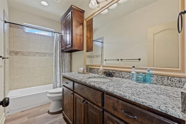 a bathroom with a granite countertop sink a toilet and shower