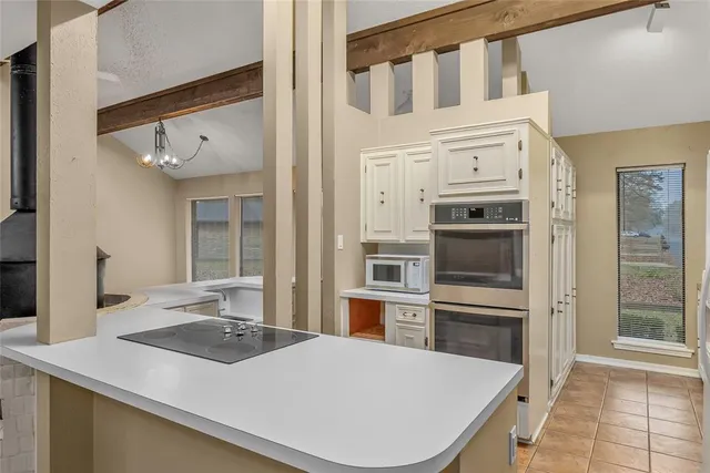 a kitchen with stainless steel appliances a stove a refrigerator a sink and white cabinets with wooden floor