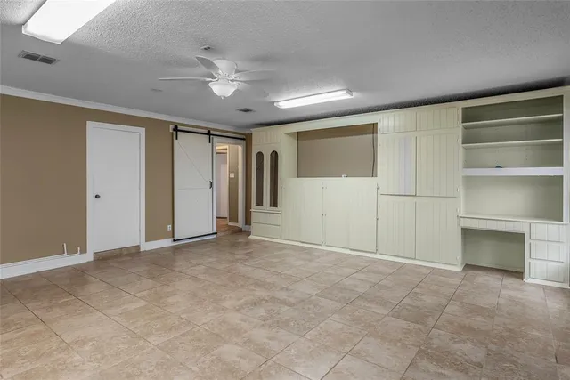 a view of an empty room with a ceiling fan and window