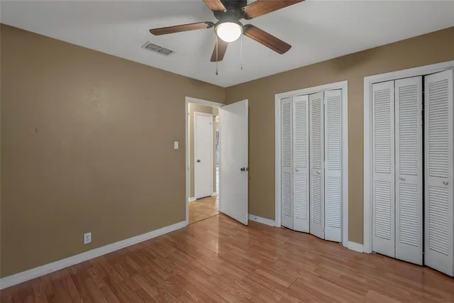 an empty room with wooden floor a ceiling fan and closet