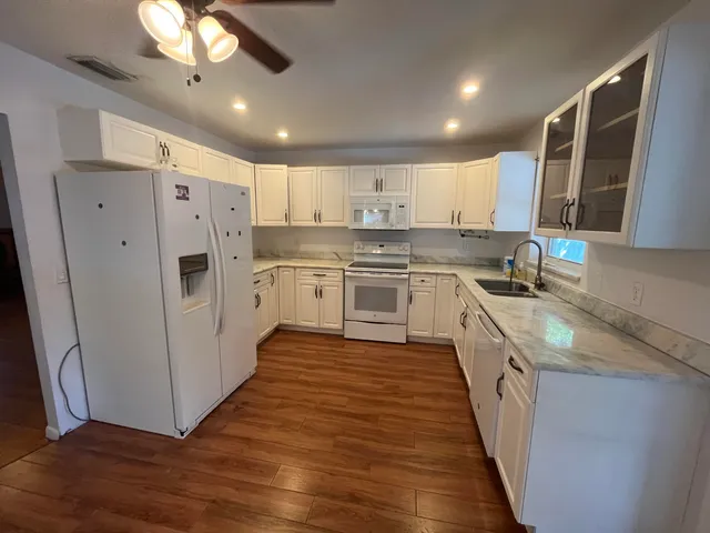 a kitchen with stainless steel appliances granite countertop a refrigerator a sink dishwasher a s stove top oven a large island with wooden floor and cabinets