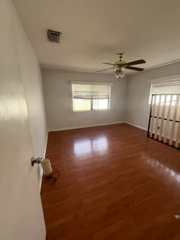 an empty room with windows and ceiling fan