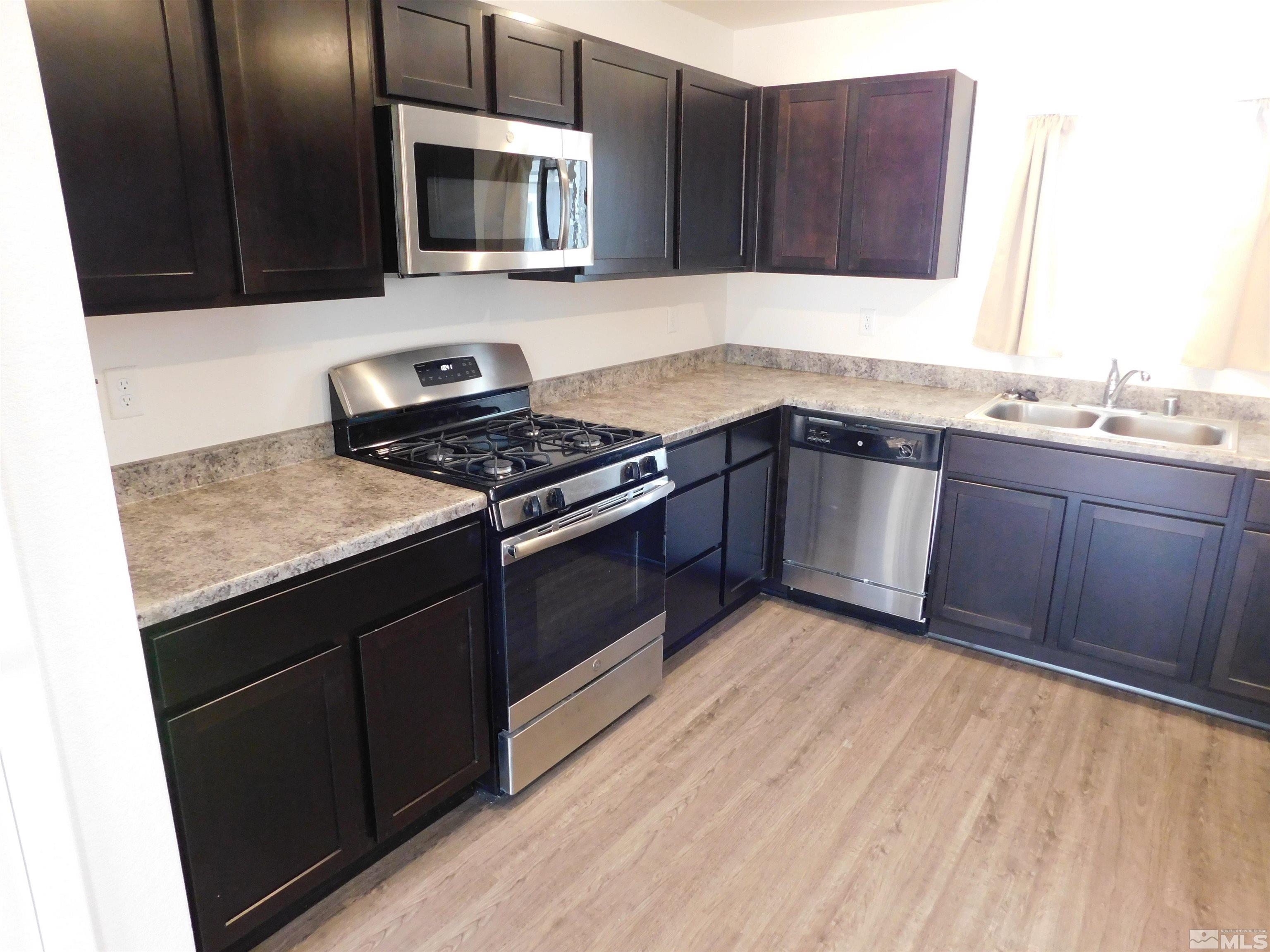239 Misty Way Dayton, NV 89403 - Photo 25 of 29 a kitchen with stainless steel appliances granite countertop a stove a sink and a microwave