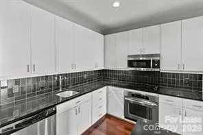 a kitchen with granite countertop white cabinets and black appliances