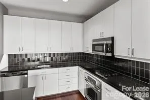 a kitchen with white cabinets and black appliances