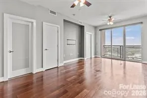 a view of an empty room with wooden floor and a window