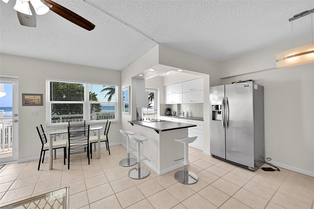 901 South Surf Road, Unit 203 Hollywood, FL 33019 - Photo 5 of 23 a kitchen with stainless steel appliances kitchen island granite countertop dining table chair and a refrigerator