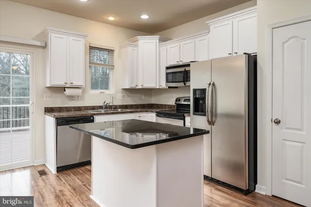 a kitchen with stainless steel appliances granite countertop a refrigerator a sink a stove a microwave and a refrigerator