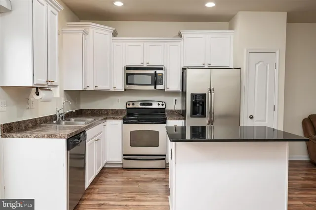 a kitchen with stainless steel appliances a stove a microwave and white cabinets