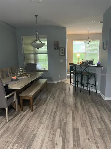 a dining room with wooden floor a chandelier a wooden table and chairs