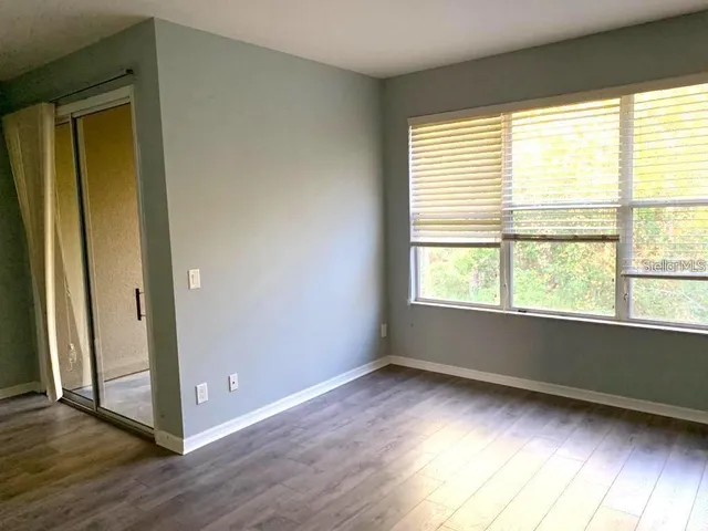 a view of an empty room with wooden floor and a window