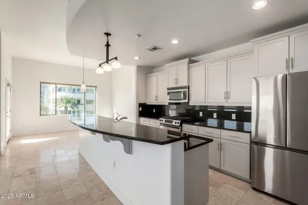 a kitchen with kitchen island a counter space a sink and stainless steel appliances