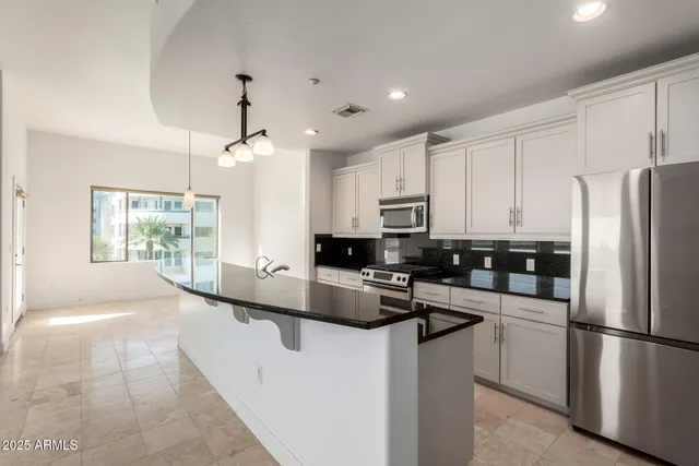 a kitchen with kitchen island a counter space a sink and stainless steel appliances