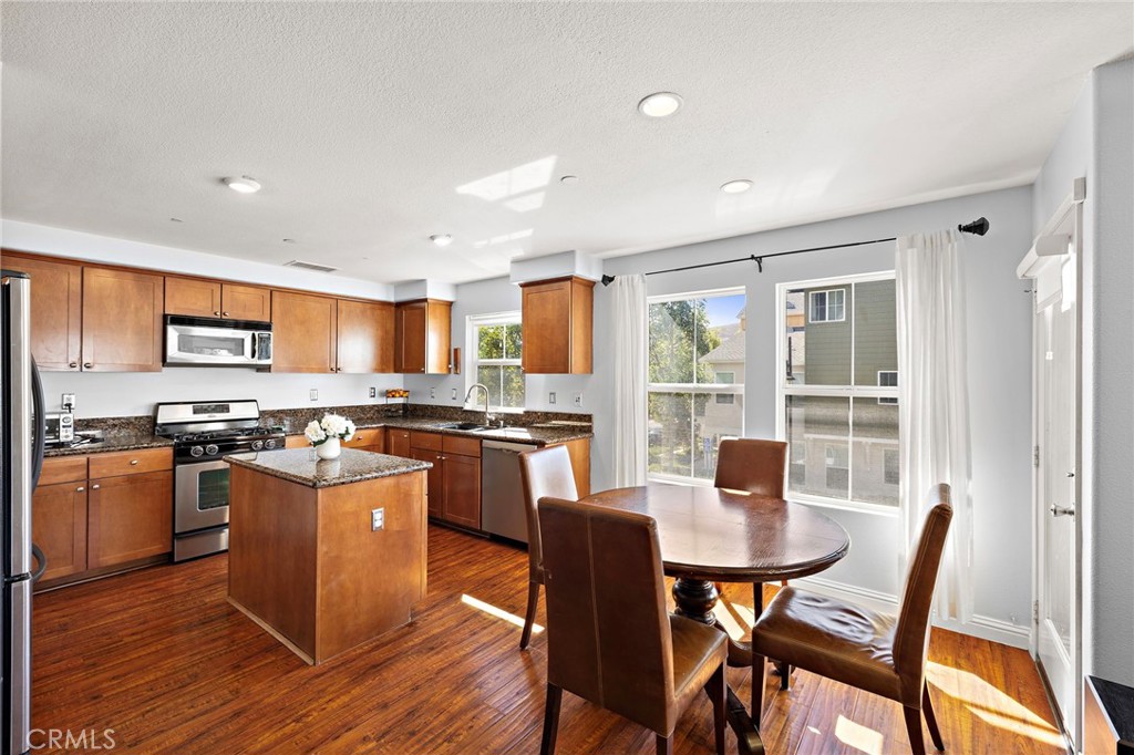 73 Platinum Circle Ladera Ranch, CA 92694 - Photo 5 of 28 a kitchen with stainless steel appliances granite countertop a stove top oven a sink dishwasher a dining table and chairs with wooden floor