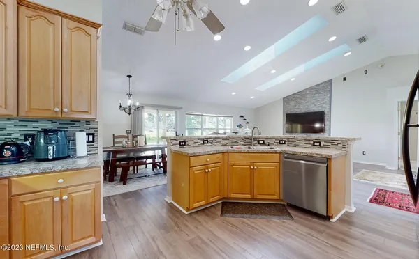 a living room with furniture kitchen view and a wooden floor