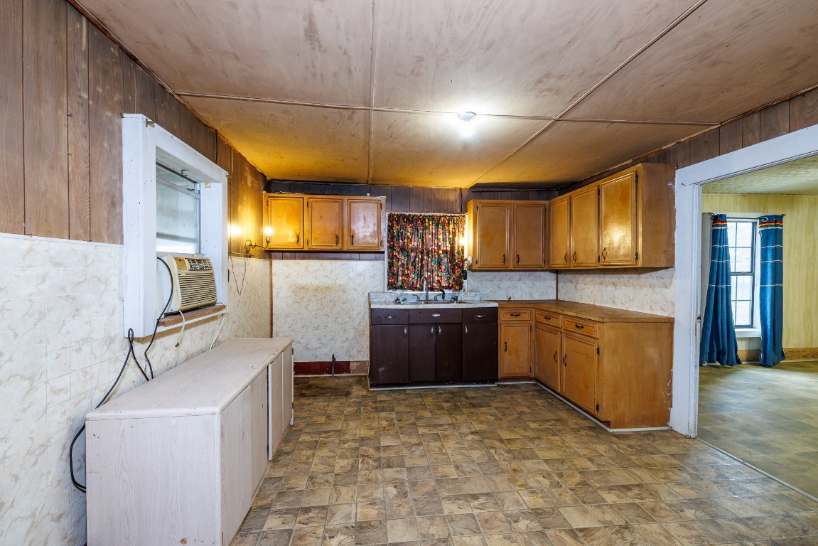 406 Carpenter Street Smiley, TX 78159 - Photo 10 of 17 Kitchen with wooden walls, brown cabinets, stone finish floors, cooling unit, and light countertops