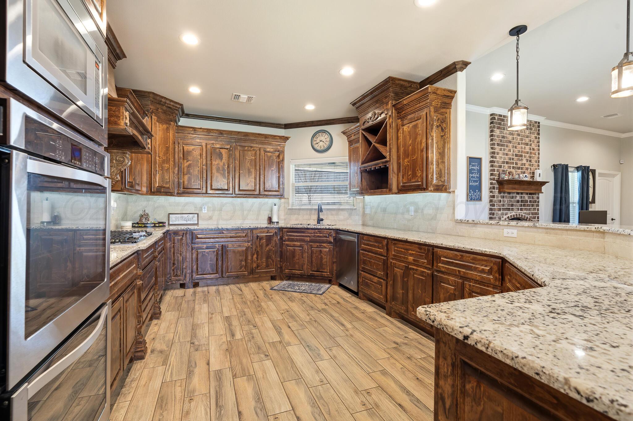 9801 Yesterday Amarillo, TX 79119 - Photo 27 of 54 a large kitchen with stainless steel appliances granite countertop plenty wooden cabinets counter space a sink and a wooden floor
