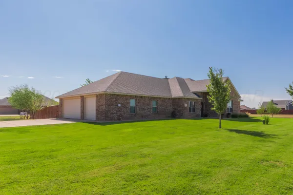 a house that is sitting in the grass with large trees