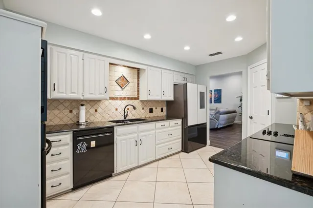 a kitchen with granite countertop white cabinets and stainless steel appliances