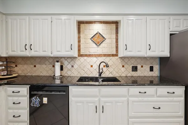 a kitchen with granite countertop white cabinets and stainless steel appliances