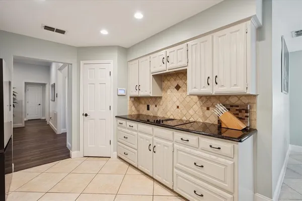 a kitchen with granite countertop white cabinets and stainless steel appliances