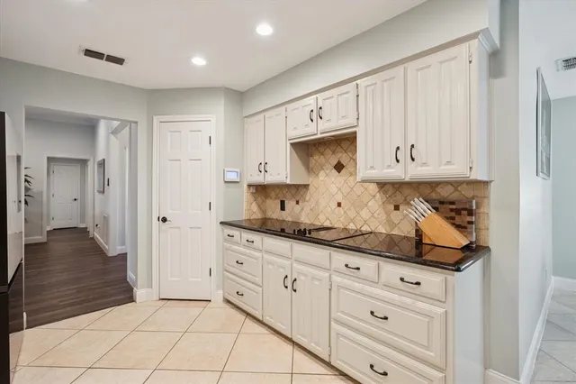 a kitchen with granite countertop white cabinets and stainless steel appliances