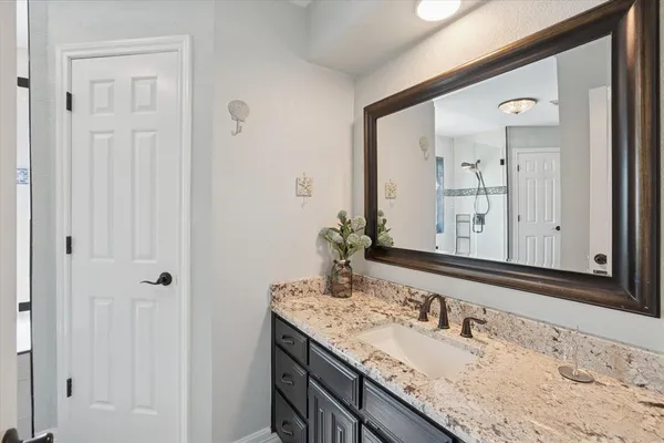a bathroom with a granite countertop sink and a mirror